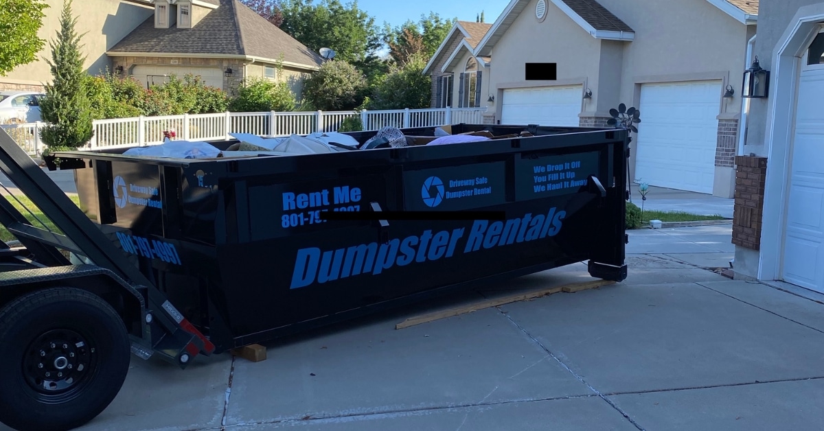 Residential dumpster placed on wooden blocks in a Utah driveway