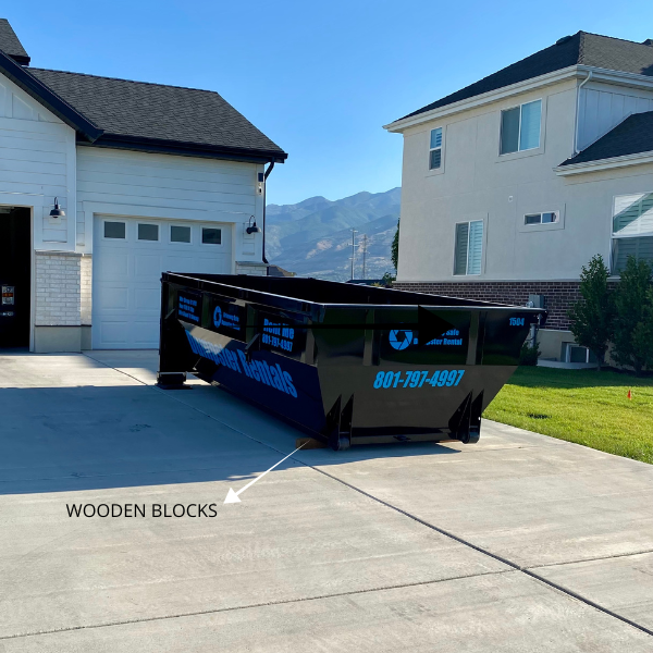 Driveway-safe dumpster placed on wooden blocks.